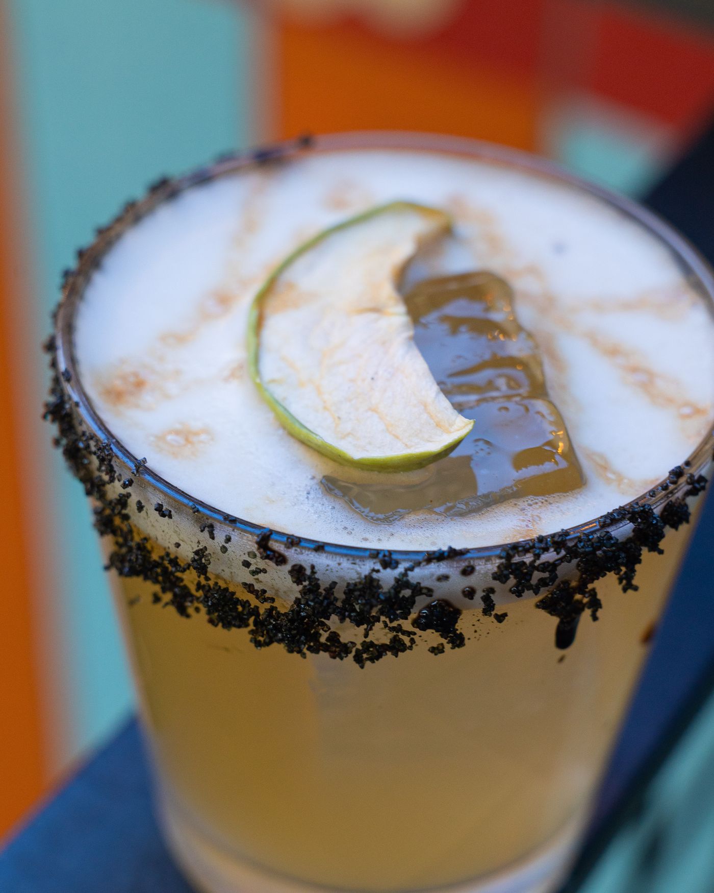 A black-salt-rimmed house cocktail with murals behind